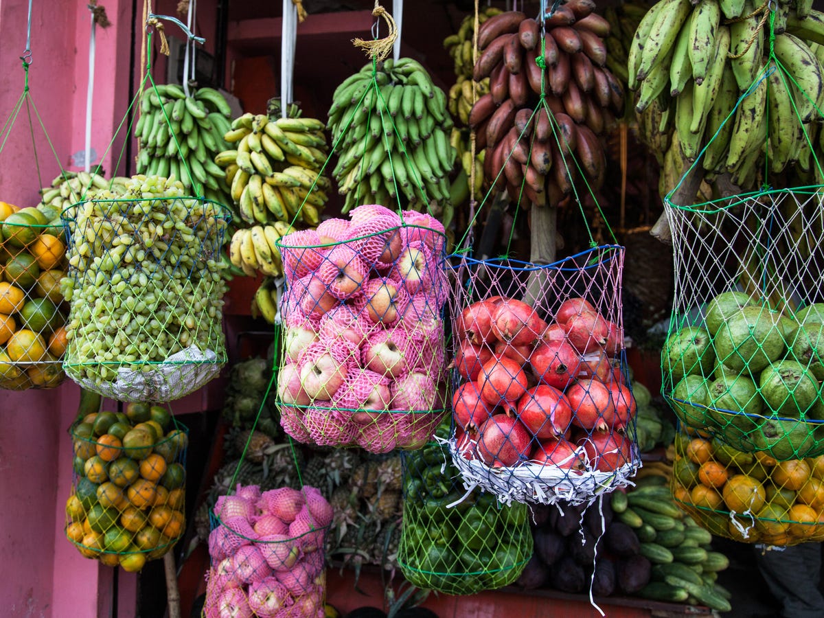 baskets of fruit, apples, limes, bananas,oranges for sale.