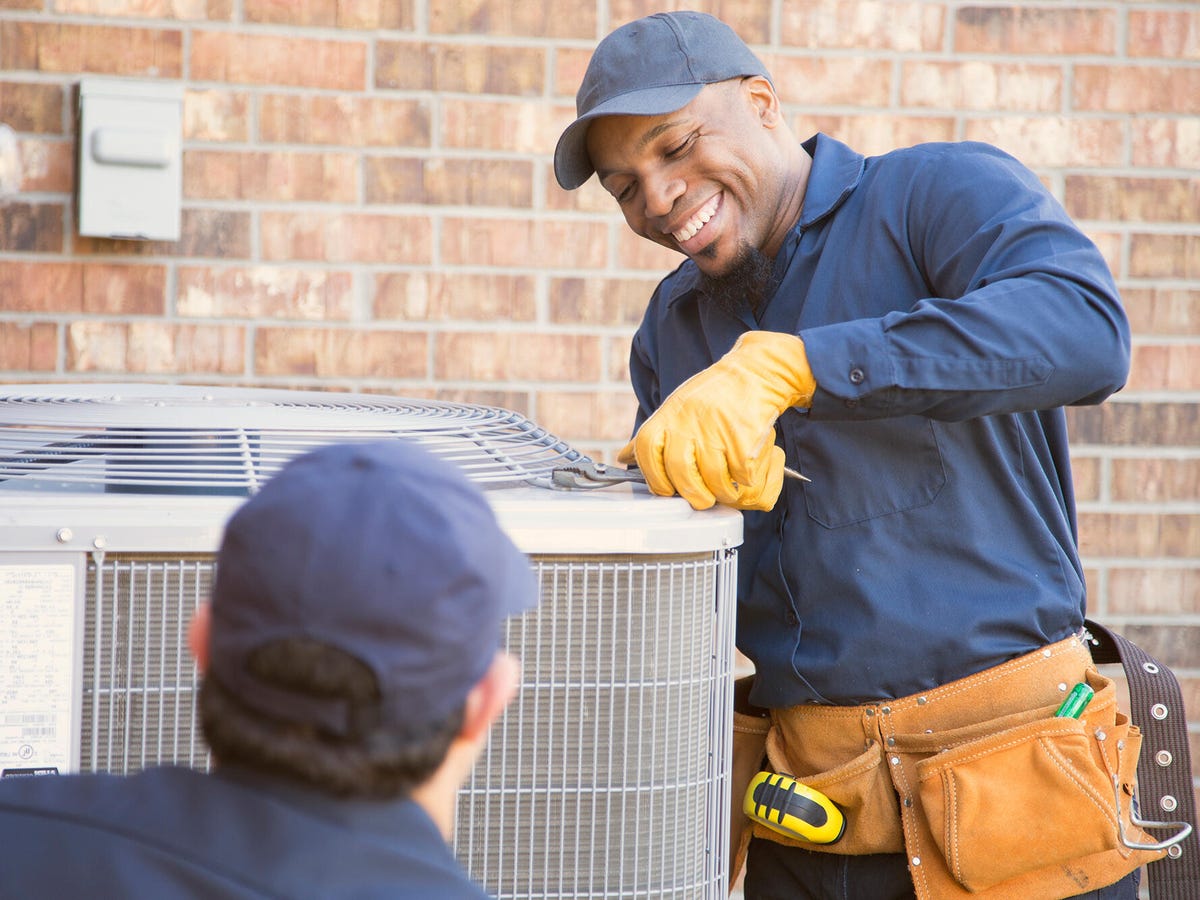 Two male technician fixing outdoor condensing unit