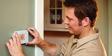 Technician mounting thermostat on the wall