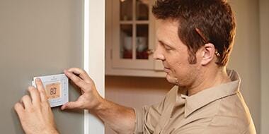 Technician mounting thermostat on the wall