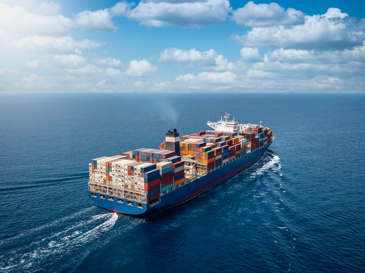 A large container cargo ship travels over calm, blue ocean A large container cargo ship travels over calm, blue ocean