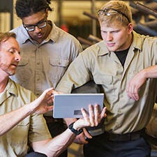 Group of men having discussion, one holing a tablet