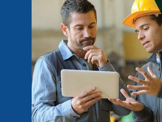 Two men having discussions, one holding a tablet