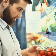 Man holding a box of tomatoes by the chiller aisle