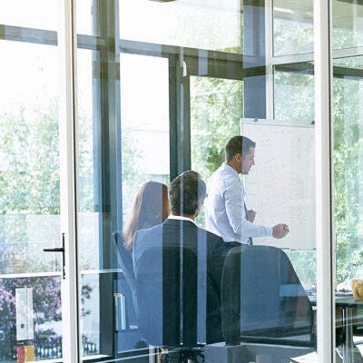 Employees in a meeting seen from the glass window