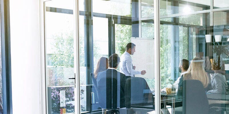 Employees in a meeting seen from the glass window