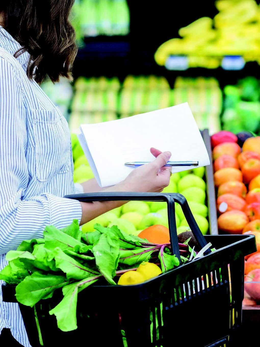 Close up shot of a woman holding black basket with veggies