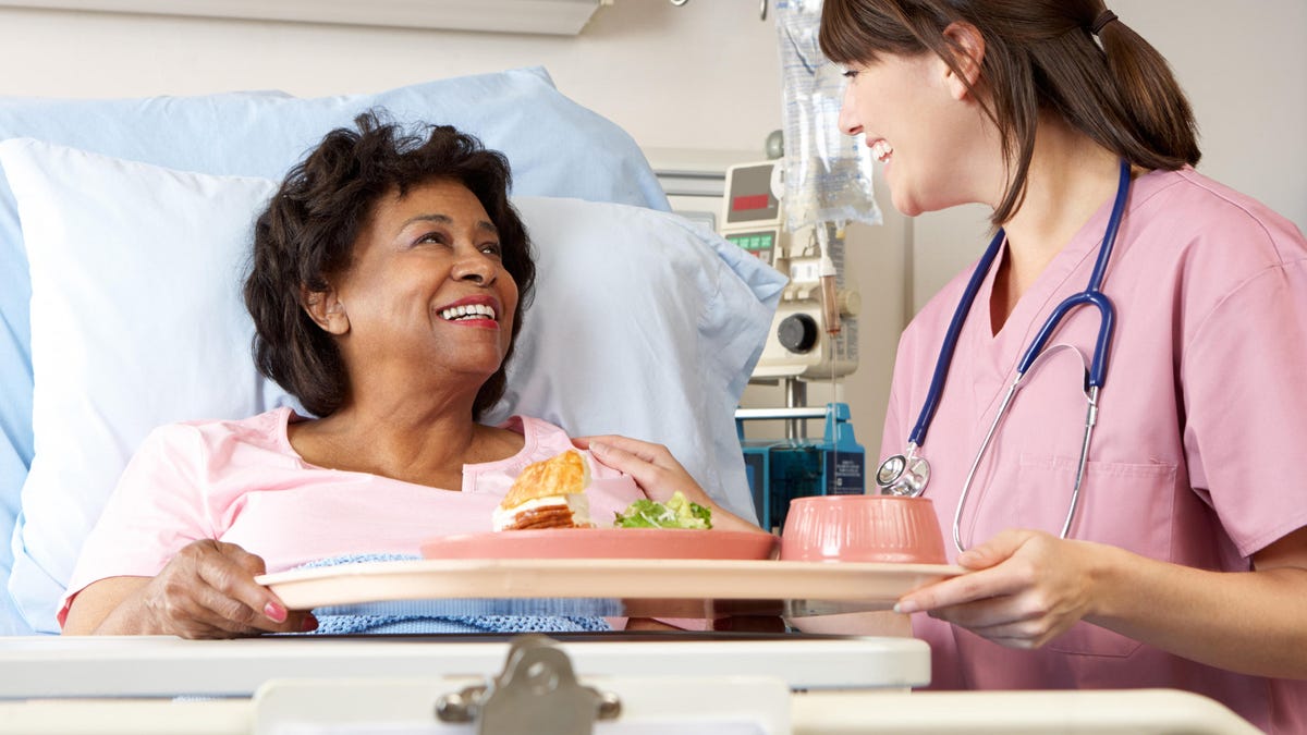 Nurse serving patient meal in bed Nurse serving patient meal in bed