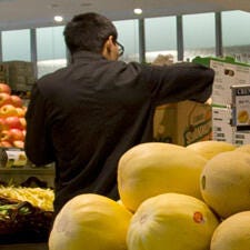 Supermarket employee arranging fruit display