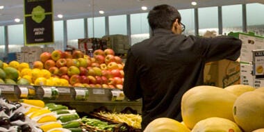 Supermarket employee arranging fruit display