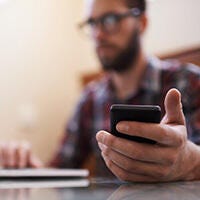 Blurry man holding a mobile phone while typing