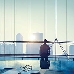 Man facing the glass wall showing the city skyline