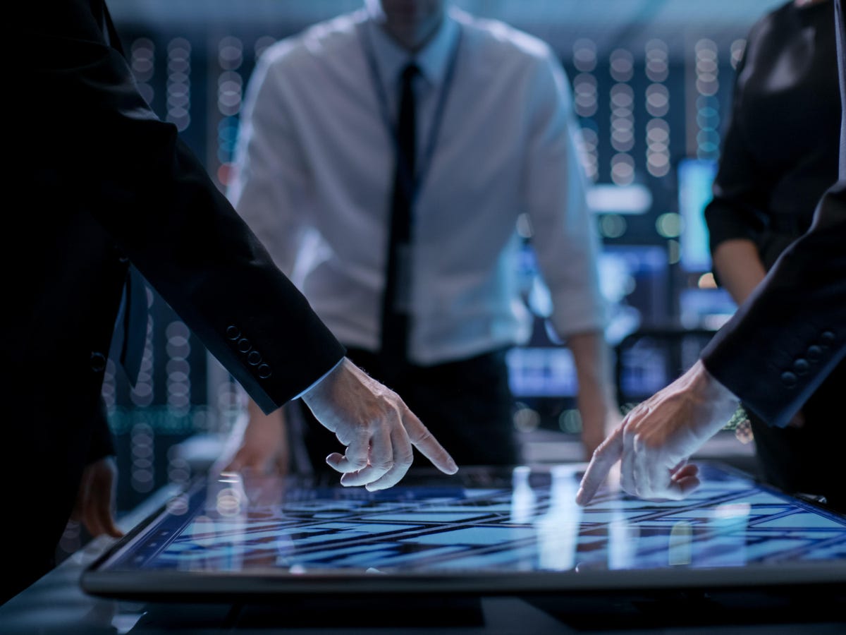 stock-photo-corporate-managers-working-at-the-table-in-monitoring-room-room-is-full-of-state-of-the-art-669170812