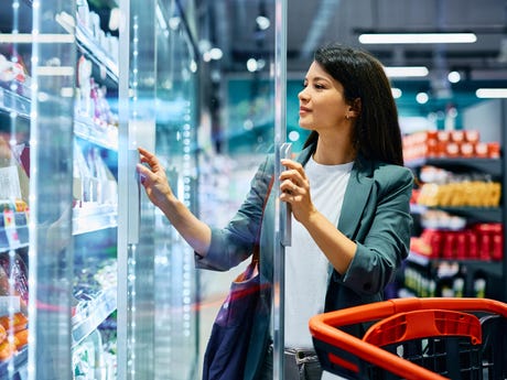 smiling-woman-buying-groceries-at-refrigerated-section-in-supermarket