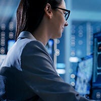 woman with glasses in front of a computer monitor