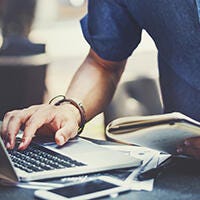 Close up of typing and holding a notebook at the same time