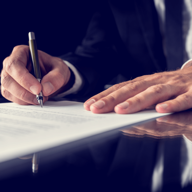 Close up of a man signing a paper