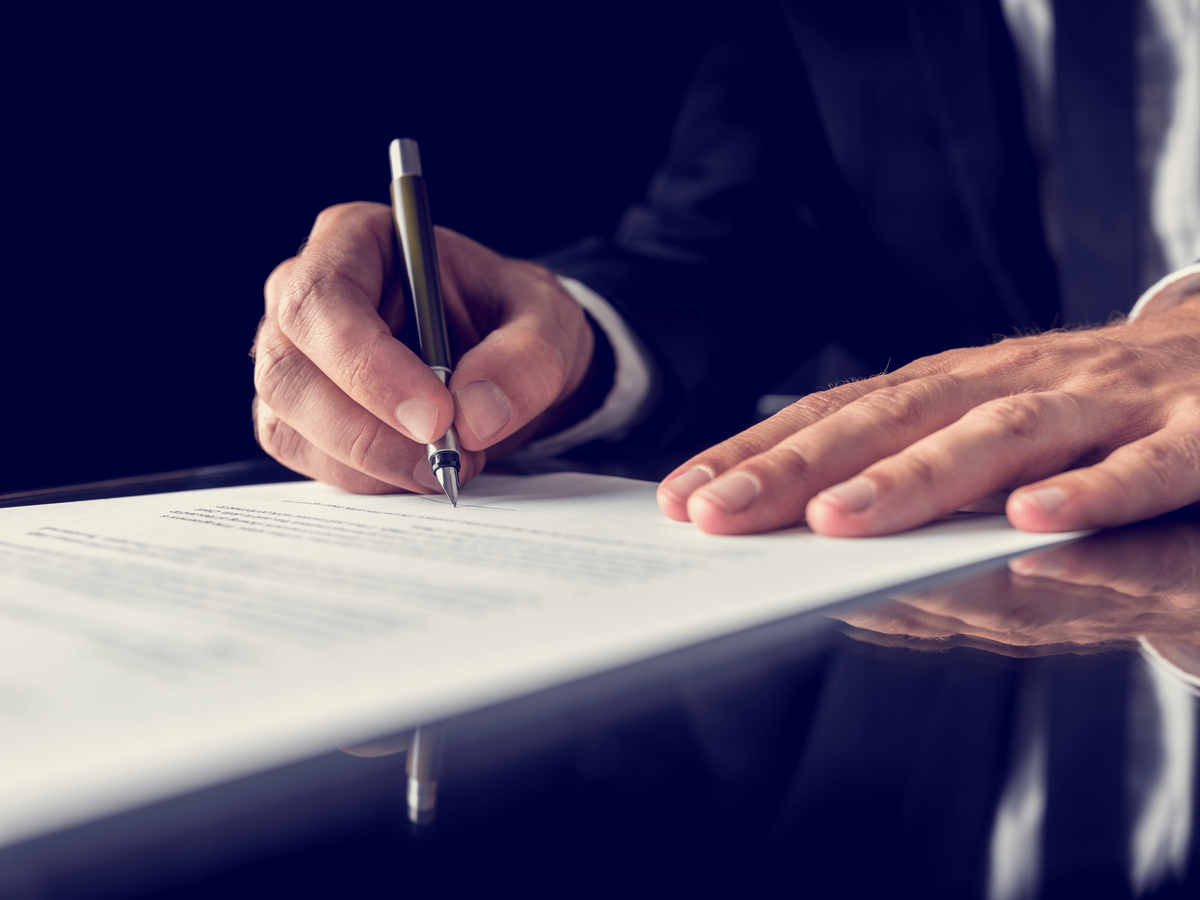 Close up of a man signing a paper