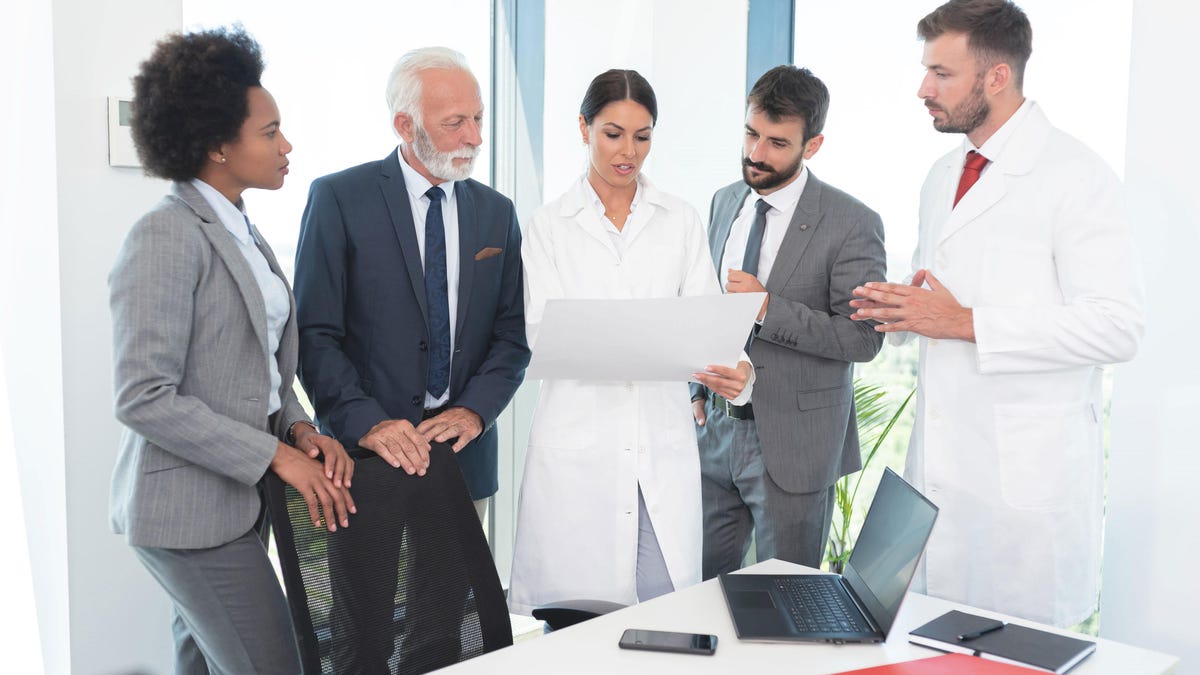 Les médecins et les hommes d’affaires se consultent debout