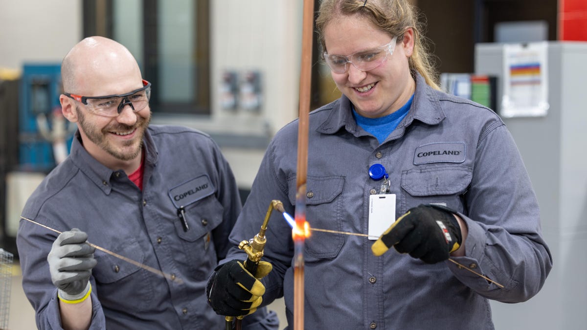 two copeland employees soldering one employee training another two copeland employees soldering one employee training another