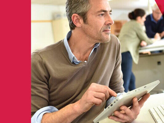 Man holding a tablet while facing the desktop