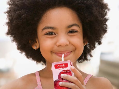 Young girl drinks from juice carton