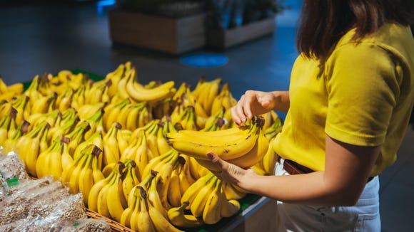 woman taking yellow bananas from the store shelf grocery shopping concept woman taking yellow bananas from the store shelf grocery shopping concept